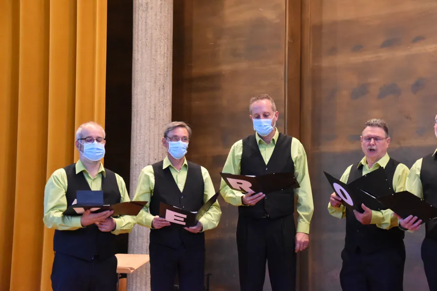 Quatre chanteurs, partitions ouvertes, lettres blanches sur les pochettes